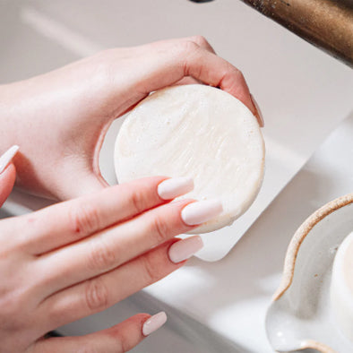 Woman using a plastic-free facial cleansing soap bar with her hands. Diminish.