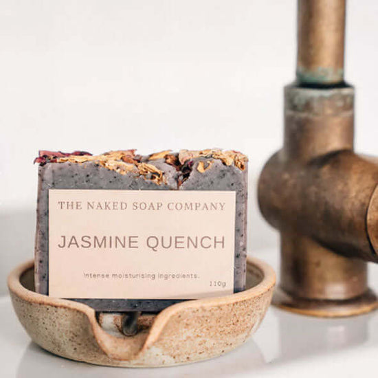 Bar of all-natural handmade jasmine quench body soap on a soap dish. 