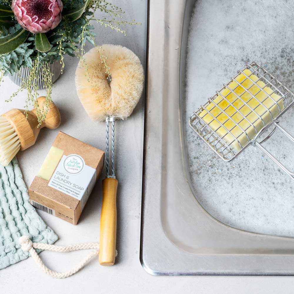 The Australian Natural Soap Company Dish & laundry soap bar on a kitchen benchtop. With a scrub brush.