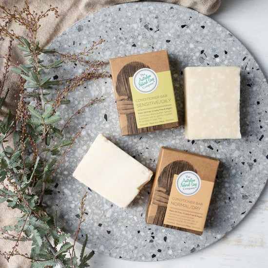 2 Australian Natural Soap Company's naked conditioner bars plus packaging. Sitting on a stone board.