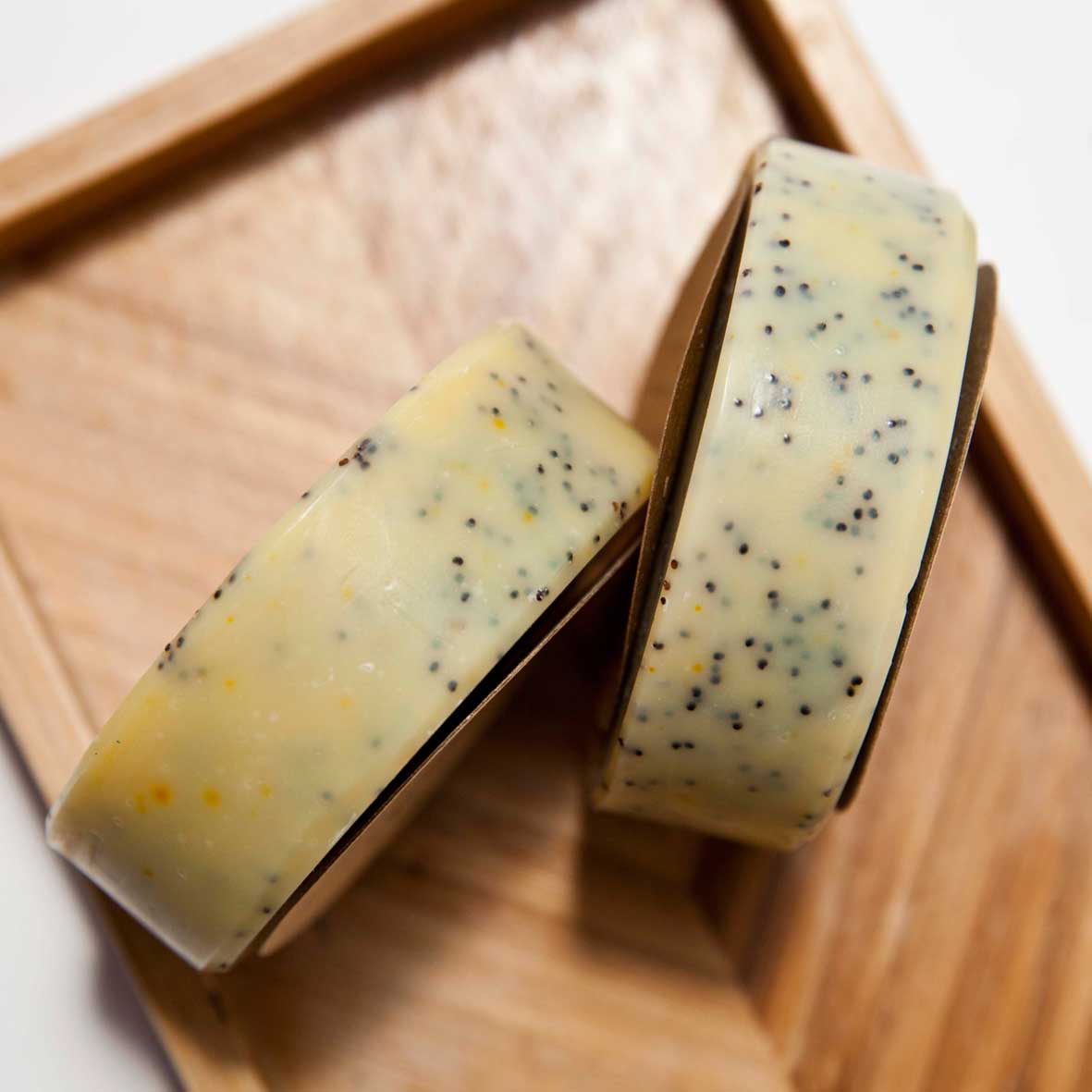 The naked soap company orange and poppy seed soap. 2 plastic-free soaps on top of a bamboo board. 