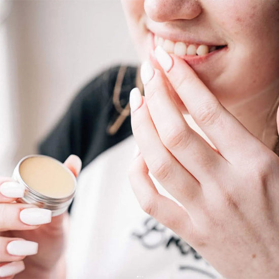 Woman using All natural lip balm and putting it on her lips. Diminish.