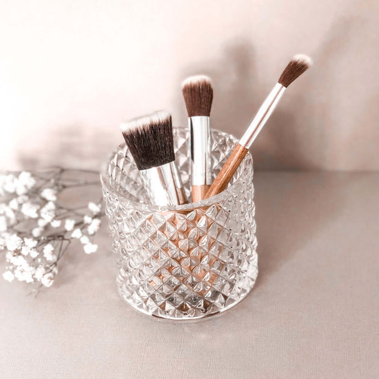 3 plastic free makeup brushes with bamboo handles in a glass jar.