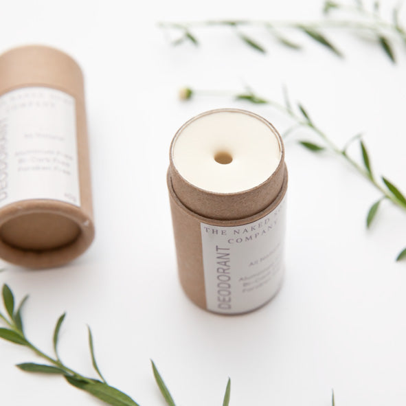 1 Tube of opened zero waste vegan and all natural deodorant with one tube on the background. On white with some leaves scattered.