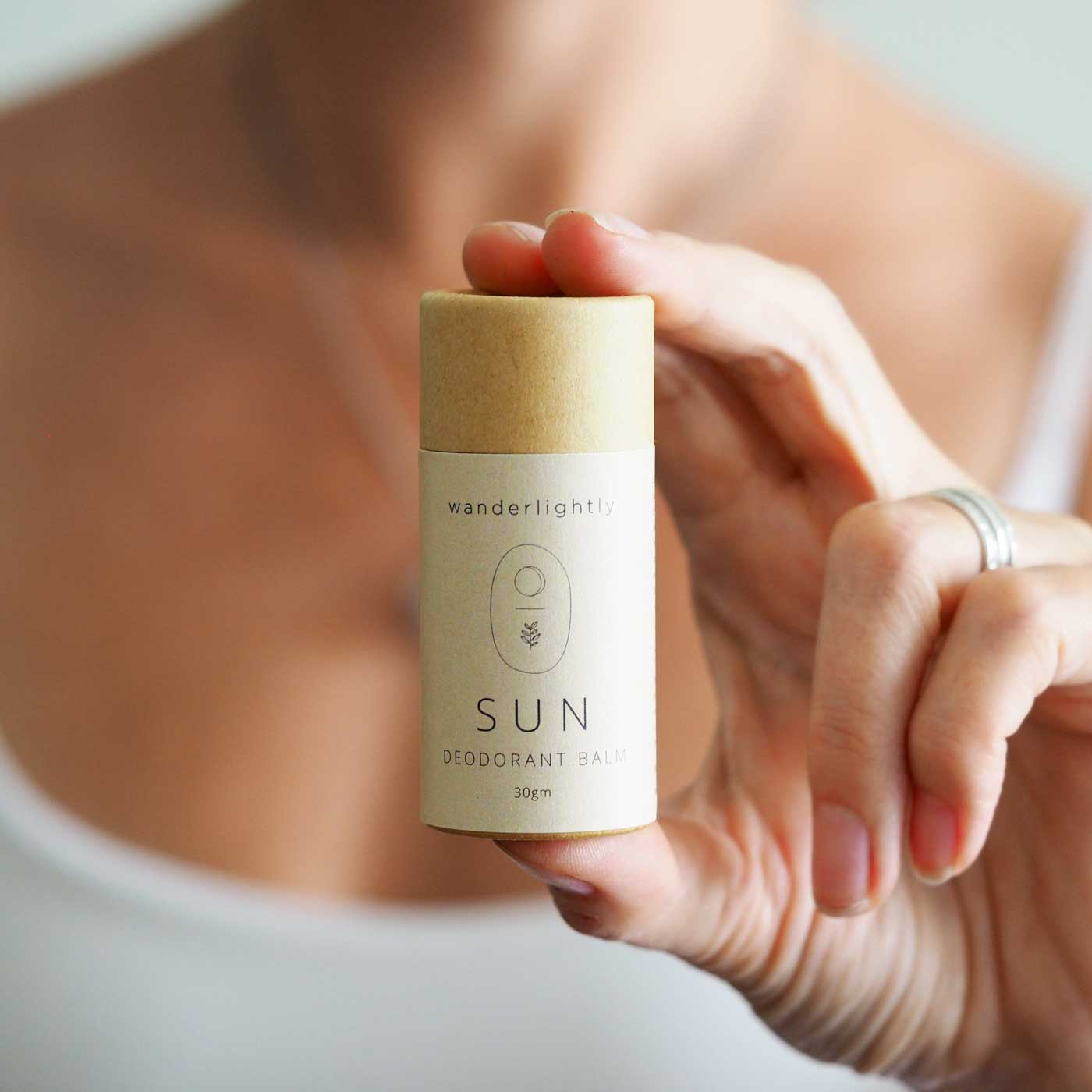 Wanderlightly all-natural sun-deodorant balm in a recyclable cardboard tube being held by a lady.