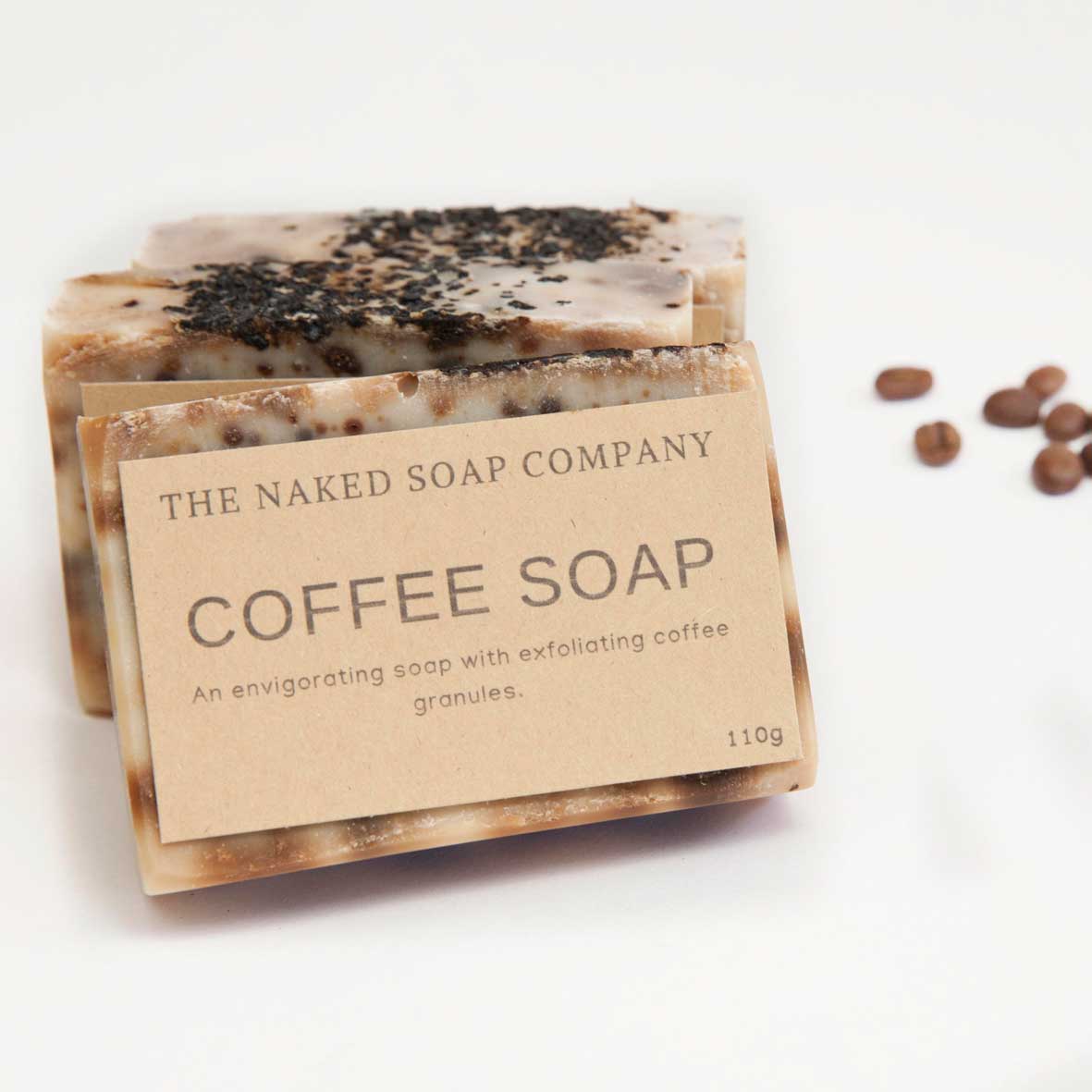 The Naked Soap Company plastic-free, vegan & non-toxic coffee soap. 3 lined up on white background with coffee beans scattered in background.