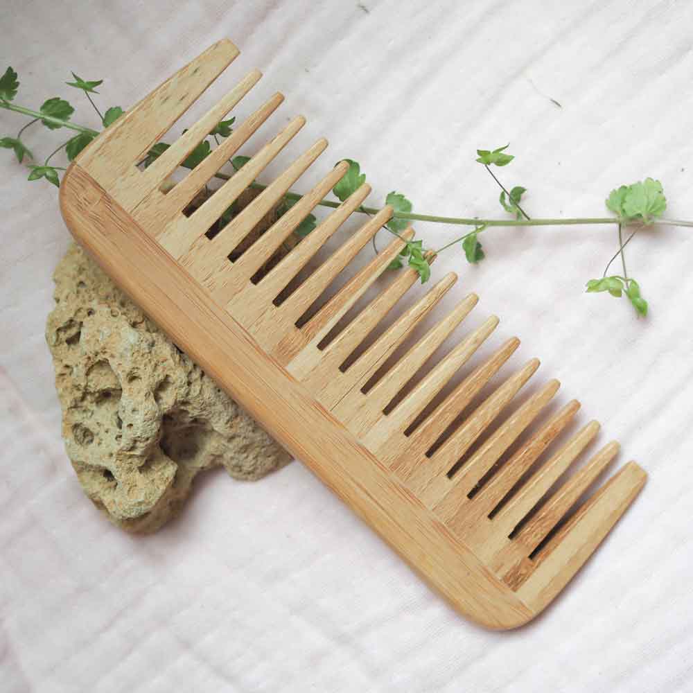 Zero waste bamboo wide tooth comb on a rock.
