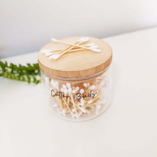 Glass jar with bamboo lid filled with bamboo cotton buds that are home compostable.