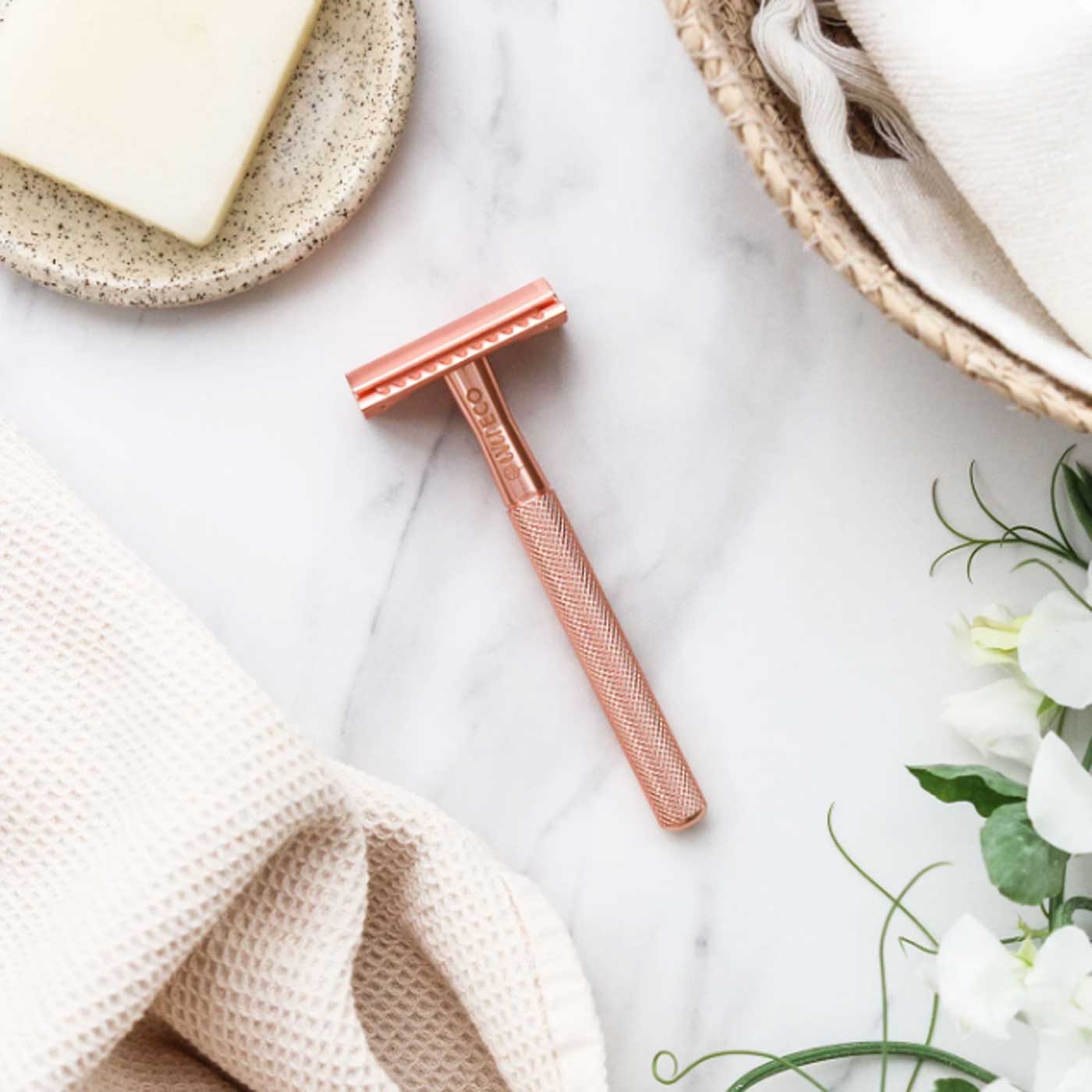 Load image into Gallery viewer, Rose gold eco-friendly reusable razor. Styled on a bathroom benchtop.

